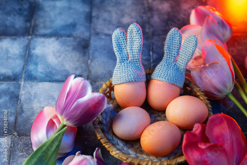 Happy Easter festive banner with colored eggs with bunny ears in a wicker basket. Fresh tulips , copy space