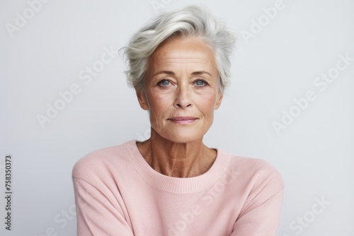 Portrait of beautiful senior woman looking at camera, isolated on grey background