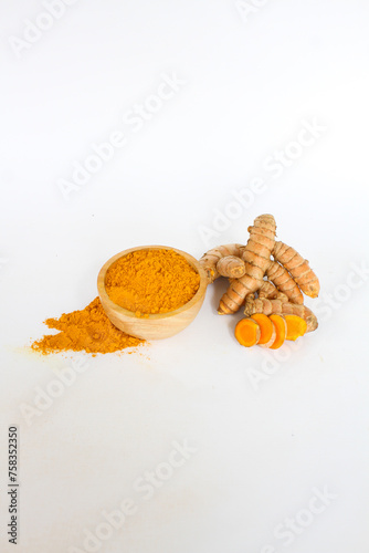 Raw turmeric material and powder in a wooden bowl