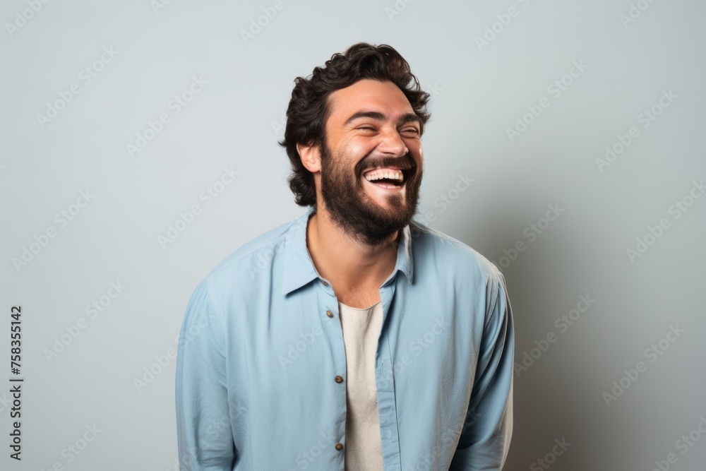 Portrait of a happy young man laughing while standing against grey background