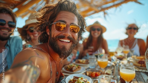 Group of joyful friends enjoying a sunny beach outing with food and drinks  taking a selfie