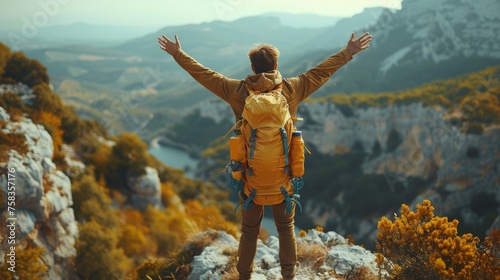Person with a backpack stands with outstretched arms, overlooking a vast mountainous landscape, feeling triumphant