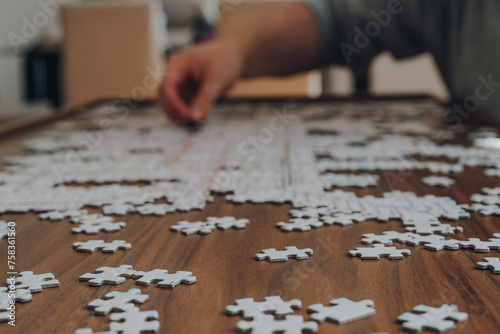 Puzzle pieces on a table, male hand placing a piece on the background.