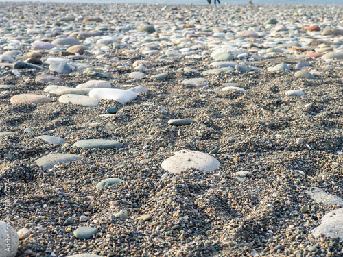 Gray sand and stones on the beach. Beach in winter. Sea coast soil.