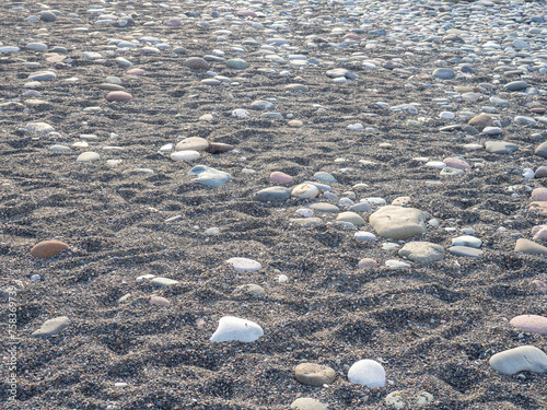 Gray sand and stones on the beach. Beach in winter. Sea coast soil.