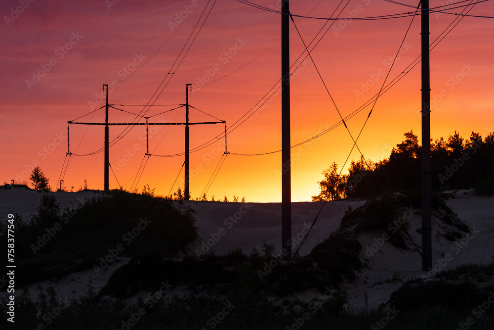 Silhouette of large overhead power lines during sunrise in Estonia, Northern Europe