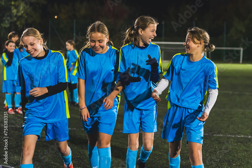 little school-age girls in soccer uniforms having fun during a break at the practice, football stadium. High quality photo