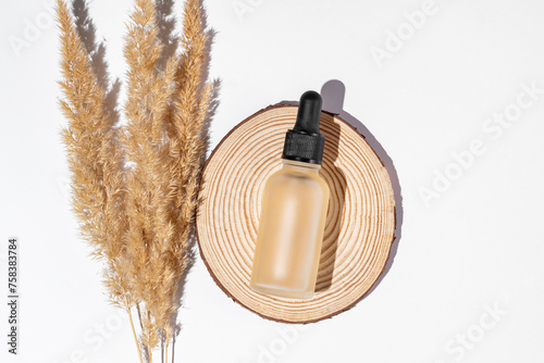 Natural essential oil, serum in matte glass bottle on a white background with dry pampas flowers. Alternative medicine, aromatic herbal beauty skin care product photo
