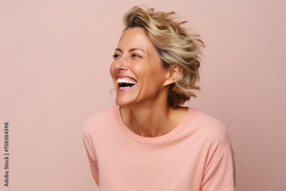 Portrait of a happy senior woman with short blonde hair laughing against pink background Portrait of a happy senior woman with short blonde hair laughing against pink background