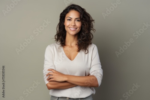 Portrait of beautiful young woman with crossed arms, over grey background