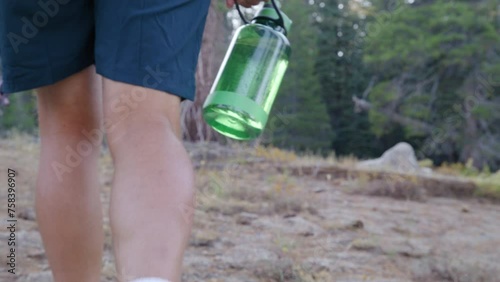 Male hiker in shorts, white socks, hiking boots steps on a grassy ground, wandering deep in the woods with eye-catching evergreen trees in the landscape. High quality 4k footage