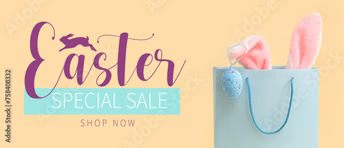 Shopping bag with fluffy bunny ears and Easter egg on beige background photo