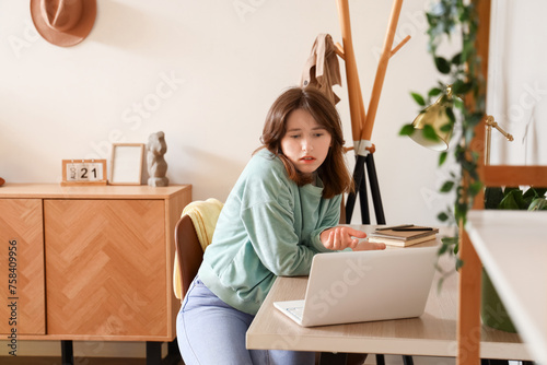 Young woman with laptop video chatting at home