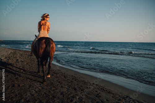 Rear view of a horsewoman riding a horse at the beach. photo