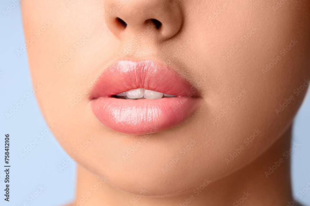 Fototapeta premium Young woman with beautiful lips on blue background, closeup