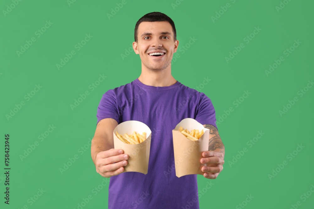 Happy young man with french fries on green background Happy young man with french fries on green background