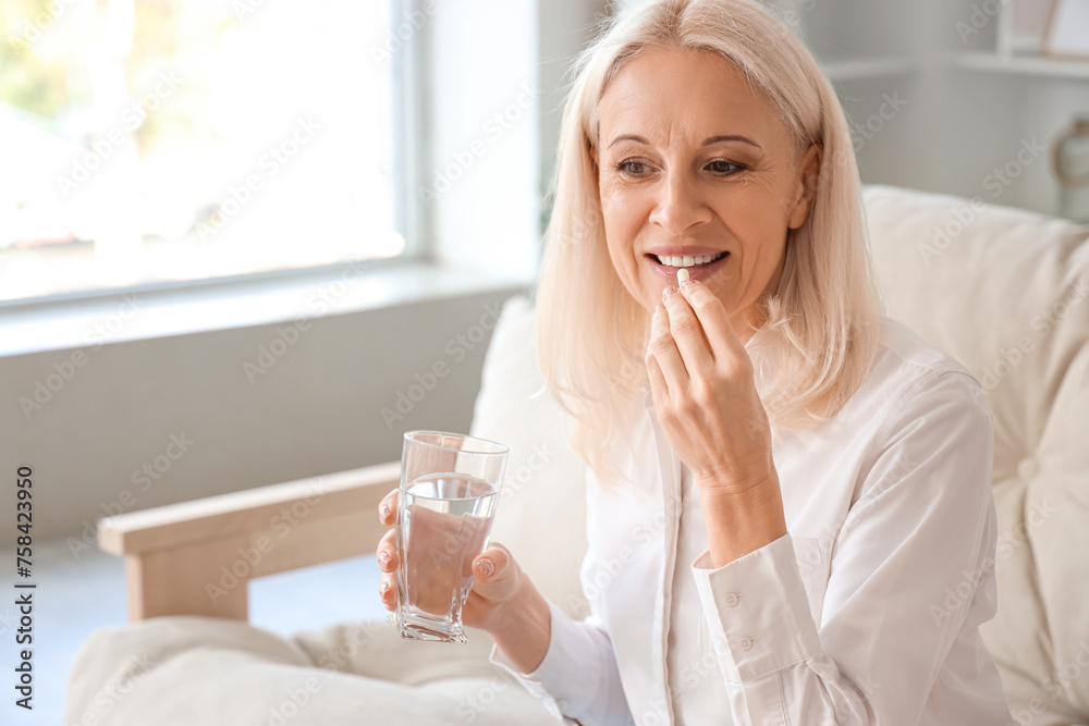 Mature woman with glass of water taking pills at home Mature woman with glass of water taking pills at home