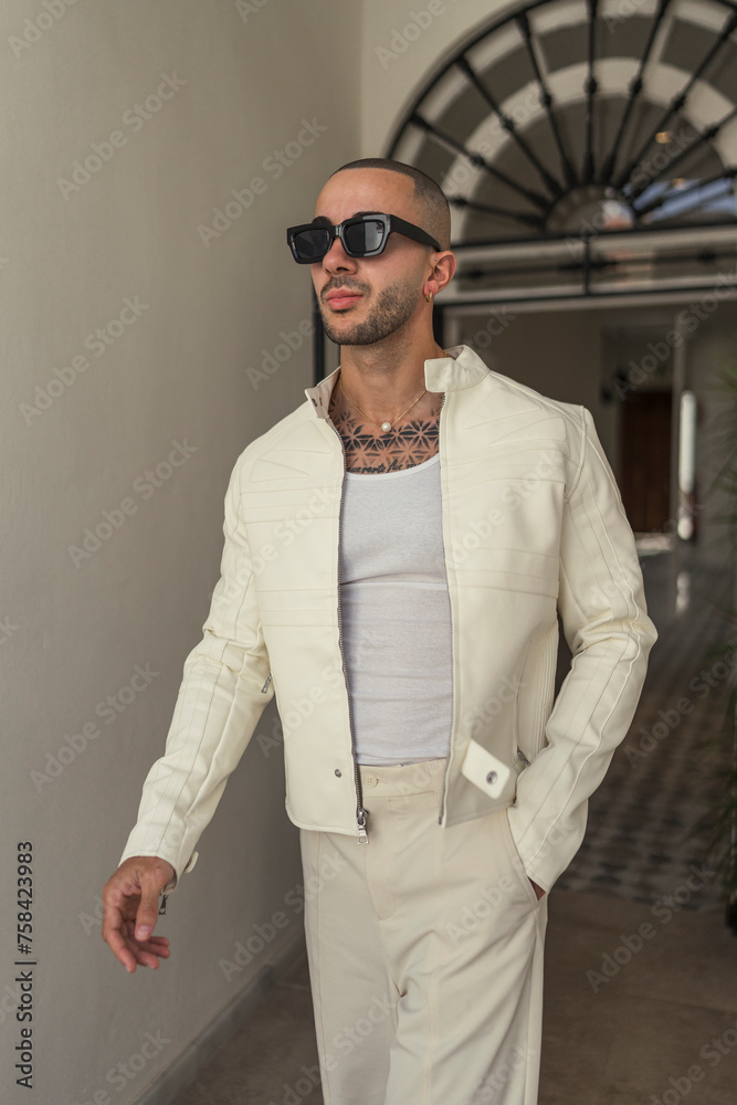 Chico joven tatuado y musculoso posando con ropa contemporánea en el hall de un hotel Chico joven tatuado y musculoso posando con ropa contemporánea en el hall de un hotel