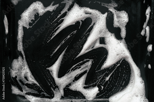 Texture of white foam and soap on a dark background. Abstract pattern. Concept of washing an oil pan or black car.