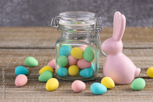 Easter composition with pink bunny and a jar with colorful candies.