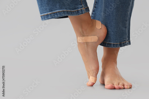 Female legs with plasters on grey background. Uncomfortable shoes concept