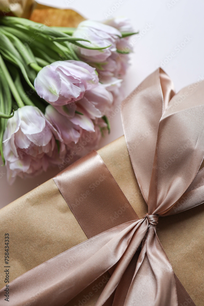 Bouquet of pink tulips and a gift box with a bow, festive concept Bouquet of pink tulips and a gift box with a bow, festive concept