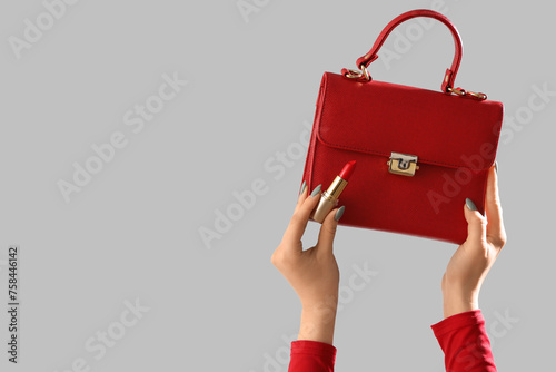 Female hands with stylish women's bag and lipstick on grey background