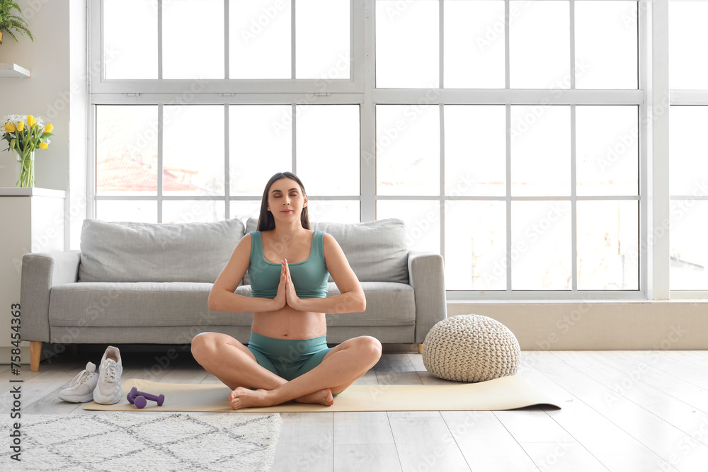 Sporty pregnant woman meditating at home Sporty pregnant woman meditating at home