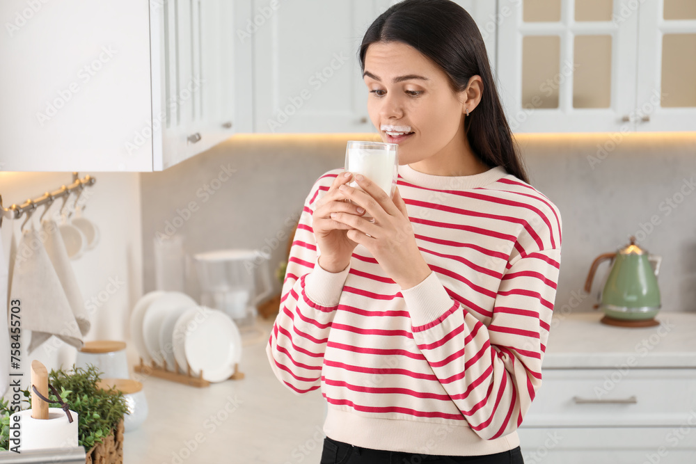 Cute woman with milk mustache drinking tasty dairy drink in kitchen. Space for text Cute woman with milk mustache drinking tasty dairy drink in kitchen. Space for text