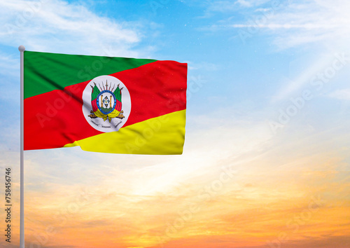 3D illustration of a Rio Grande do Sul flag extended on a flagpole and in the background a beautiful sky with a sunset