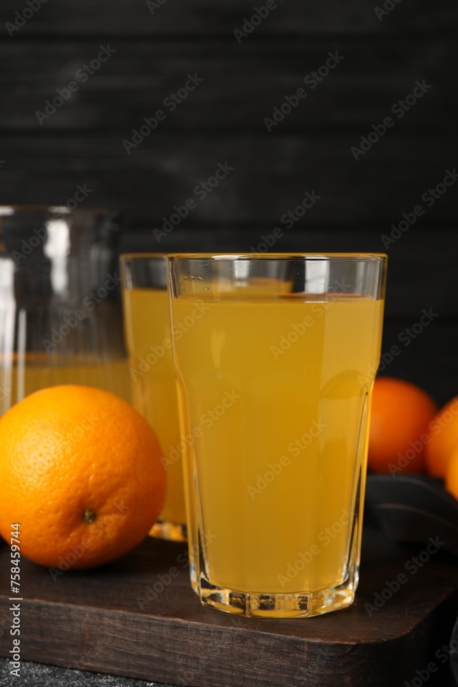 Many ripe oranges and fresh juice on dark grey table Many ripe oranges and fresh juice on dark grey table