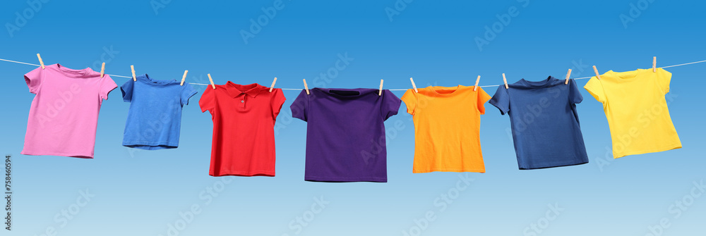 Colorful t-shirts drying on washing line against blue sky, banner design