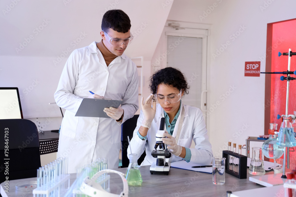 Obraz premium Young chemists working with microscope in laboratory