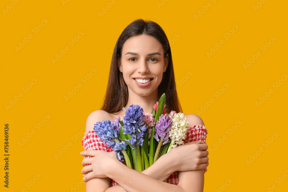 Happy smiling young woman with hyacinth flowers on yellow background Happy smiling young woman with hyacinth flowers on yellow background