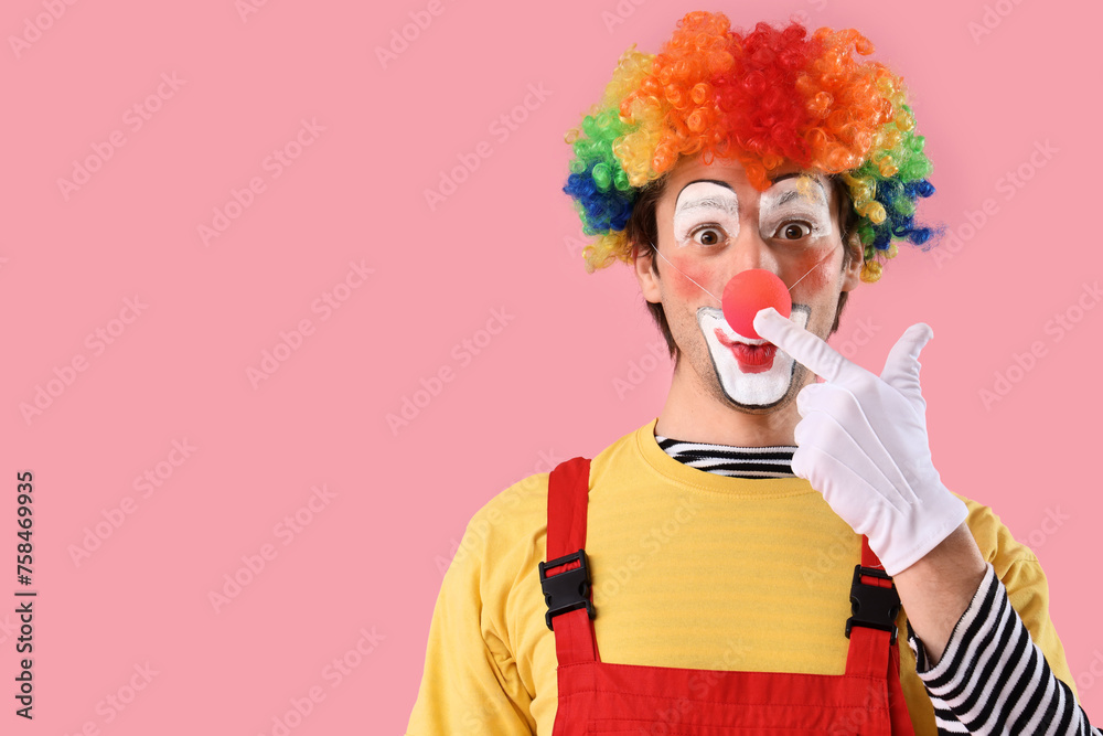 Portrait of clown touching his red nose on pink background. April Fool's day celebration Portrait of clown touching his red nose on pink background. April Fool's day celebration