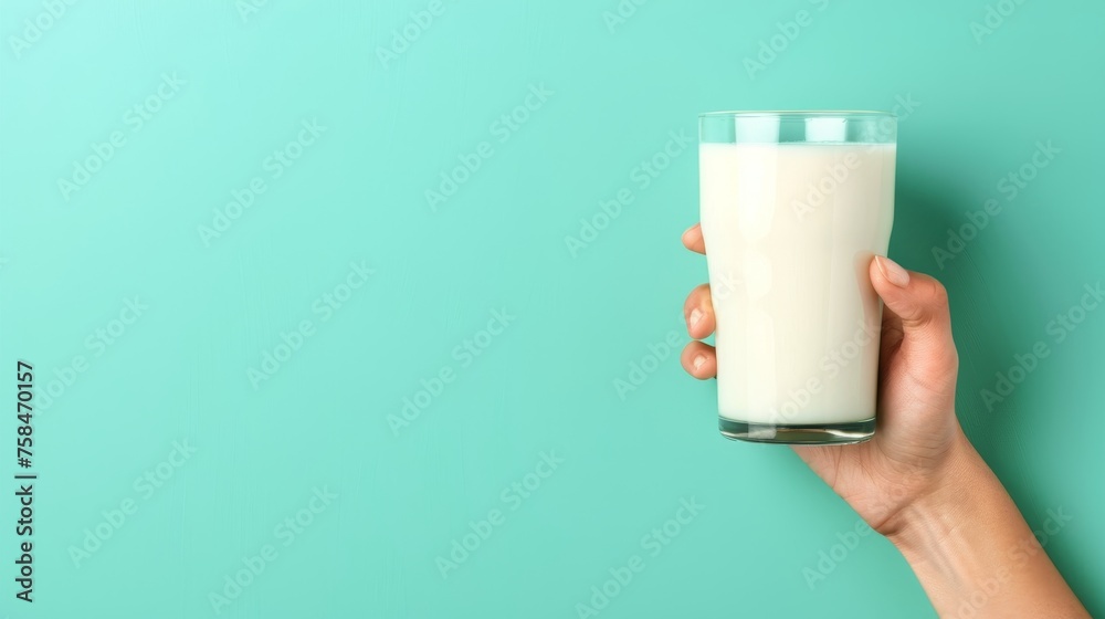 Hand holding milk glass on pastel background with ample copy space for text placement Hand holding milk glass on pastel background with ample copy space for text placement