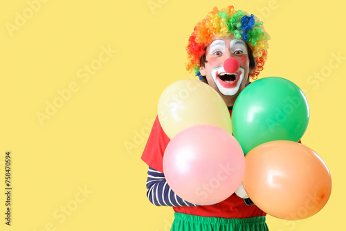 Portrait of clown with balloons on yellow background. April Fool's day celebration