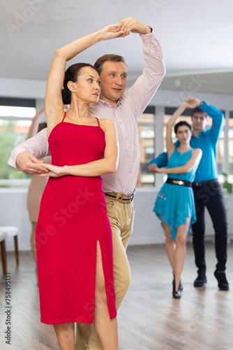 Group of different ages active people in festive clothes dancing dance movements in modern studio