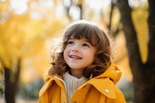 Portrait of adorable little girl in yellow coat at autumn park.