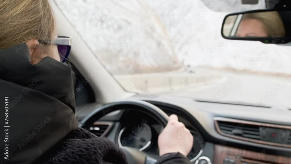 Confident woman in black sunglasses driving a car, rear view from behind the driver's shoulder. Road trip out of town. Confident woman in black sunglasses driving a car, rear view from behind the driver's shoulder. Road trip out of town.