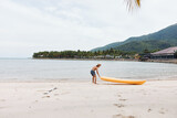 Happy Asian Man Kayaking in Tropical Paradise: Adventure, Fun, and Leisure on a Sunlit Beach
