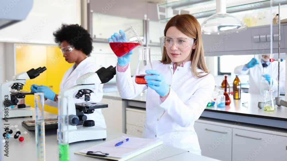 Female lab specialist examining some samples and writing down in the record Female lab specialist examining some samples and writing down in the record