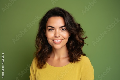 Portrait of beautiful young woman smiling at camera, over green background