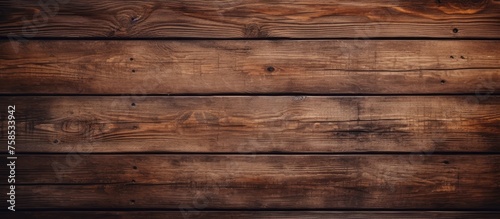 A closeup of a brown hardwood plank wall with a blurred background, showcasing the intricate pattern of the wood grain. This building material is an example of beautiful wood flooring