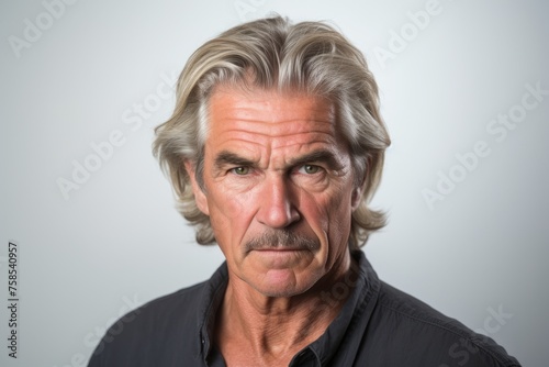 Portrait of senior man with grey hair over grey background. Looking at camera.