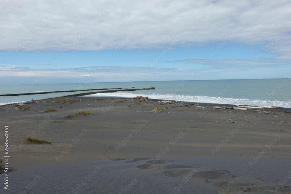 Footsteps leading down black sand-dunes to waters edge.