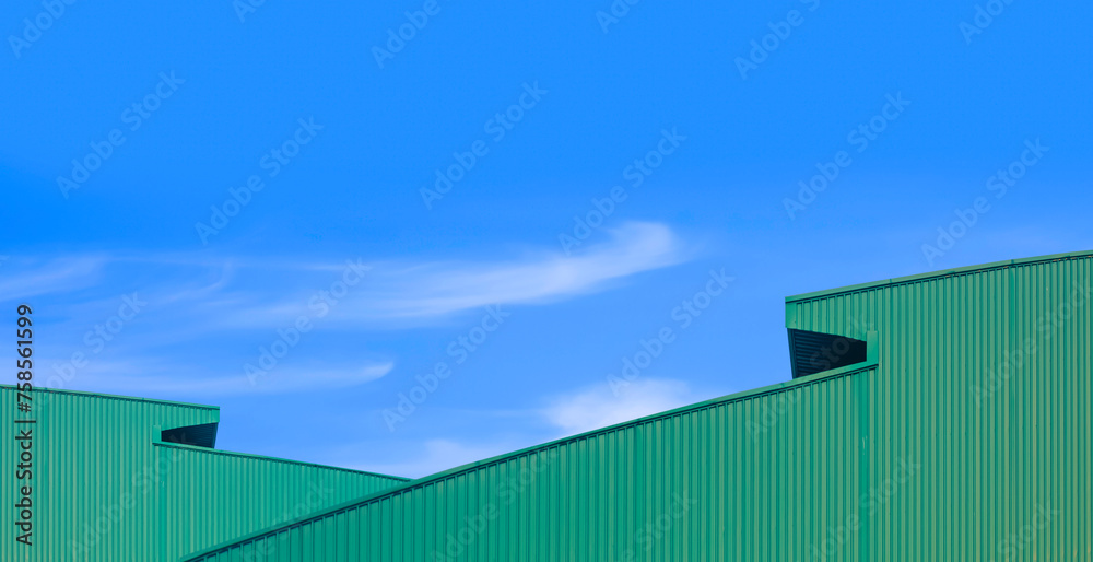 Two green corrugated metal curved roofs of modern industrial warehouse buildings against blue sky background in minimal style, Panoramic view Two green corrugated metal curved roofs of modern industrial warehouse buildings against blue sky background in minimal style, Panoramic view