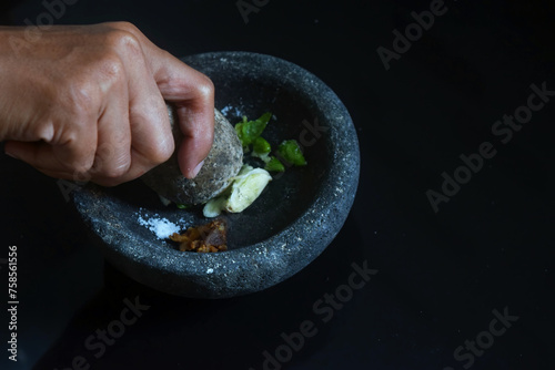 A girl hand is making chili sauce using a stone blender called Layah