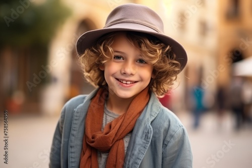 Portrait of a cute little boy wearing a hat and scarf on a street © Igor