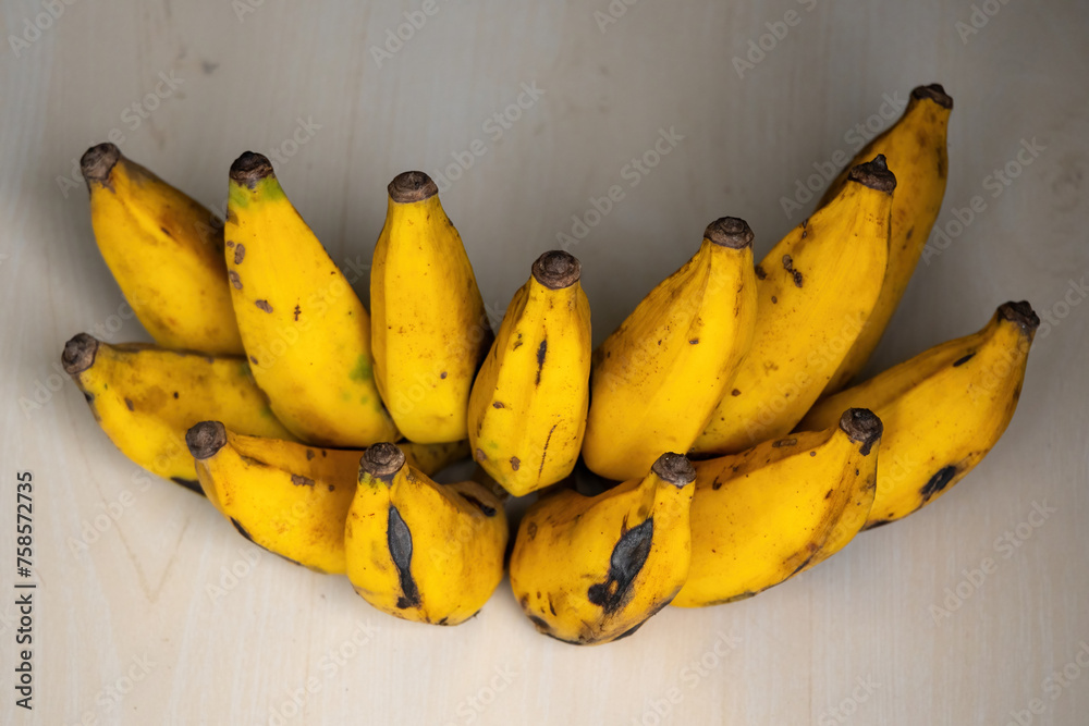A bunch of fresh ripe bananas on a wooden background. Bananas are a nutritious fruit that has many health benefits.  - obrazy, fototapety, plakaty 